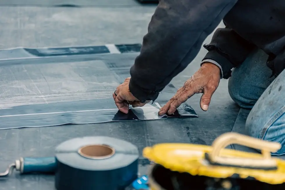 Gloved hands pressing a seam on a membrane roof with a hand roller